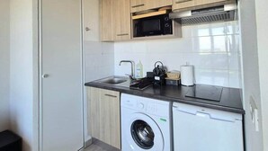 Een kleine keuken met een wasmachine, een magnetron en een spoelbak.