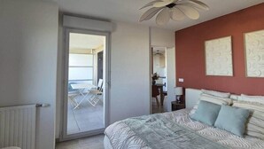 Een slaapkamer met een groot bed, een plafondventilator en uitzicht op het balkon.
