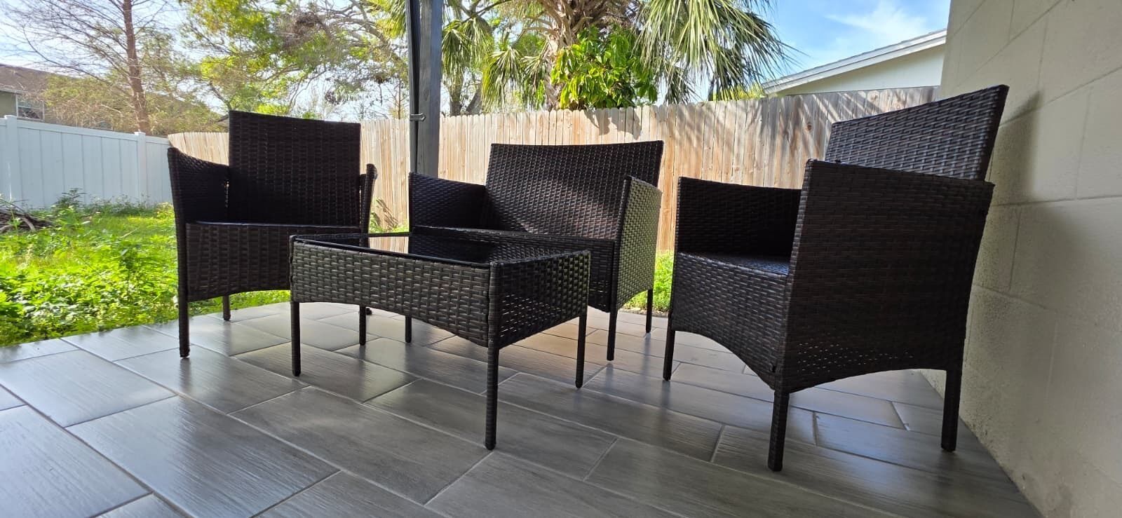 A patio with four wicker chairs and a small table.