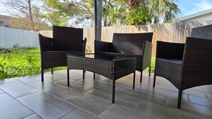 Une terrasse avec quatre chaises en osier et une petite table.