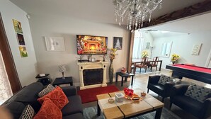Ein Wohnzimmer mit Kamin, Billardtisch und Essbereich im Hintergrund.