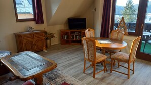 Una sala de estar acogedora con una mesa de comedor, sillas, una televisión y una estantería.