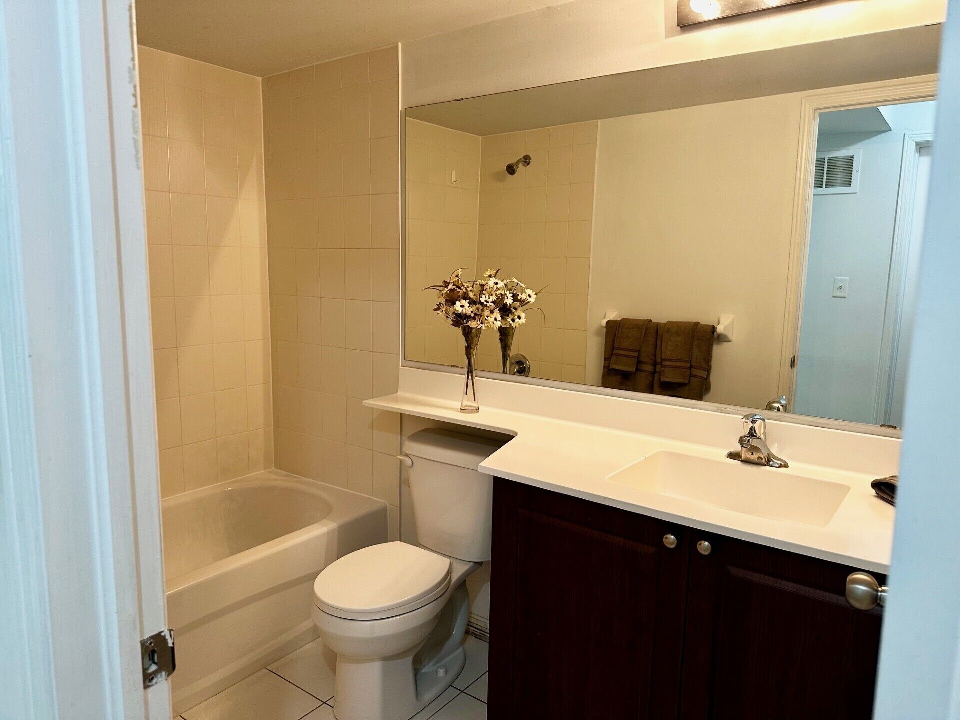 A bathroom with a bathtub, toilet, and vanity with a mirror.