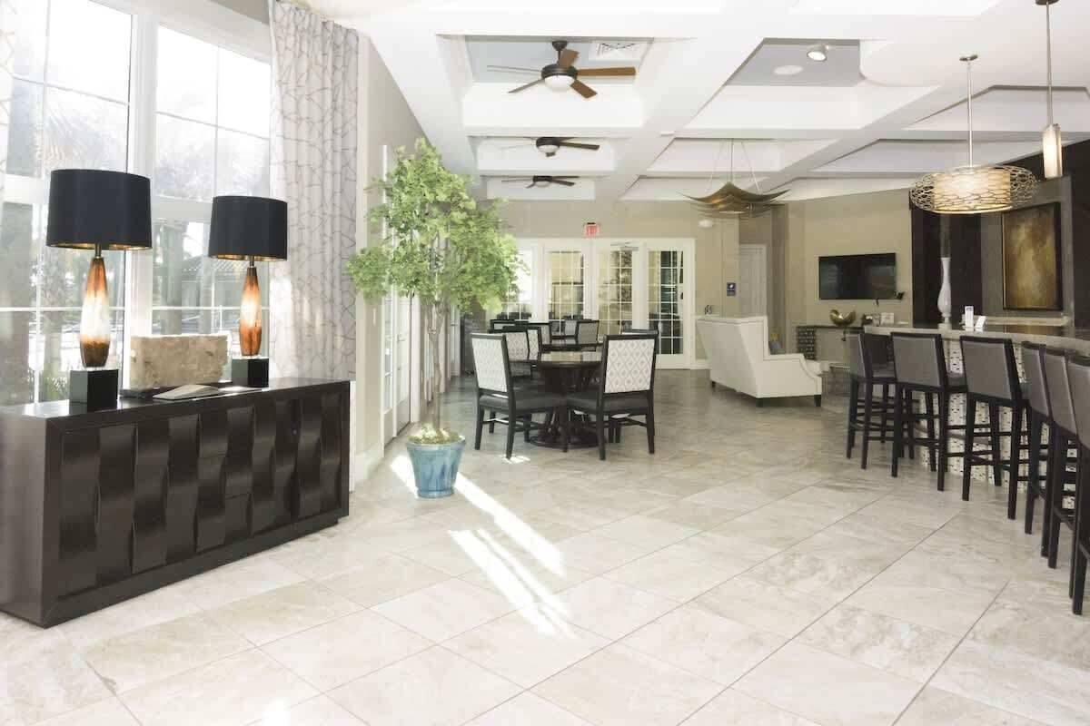 A spacious hotel lobby with a reception desk, dining area, and a large plant.