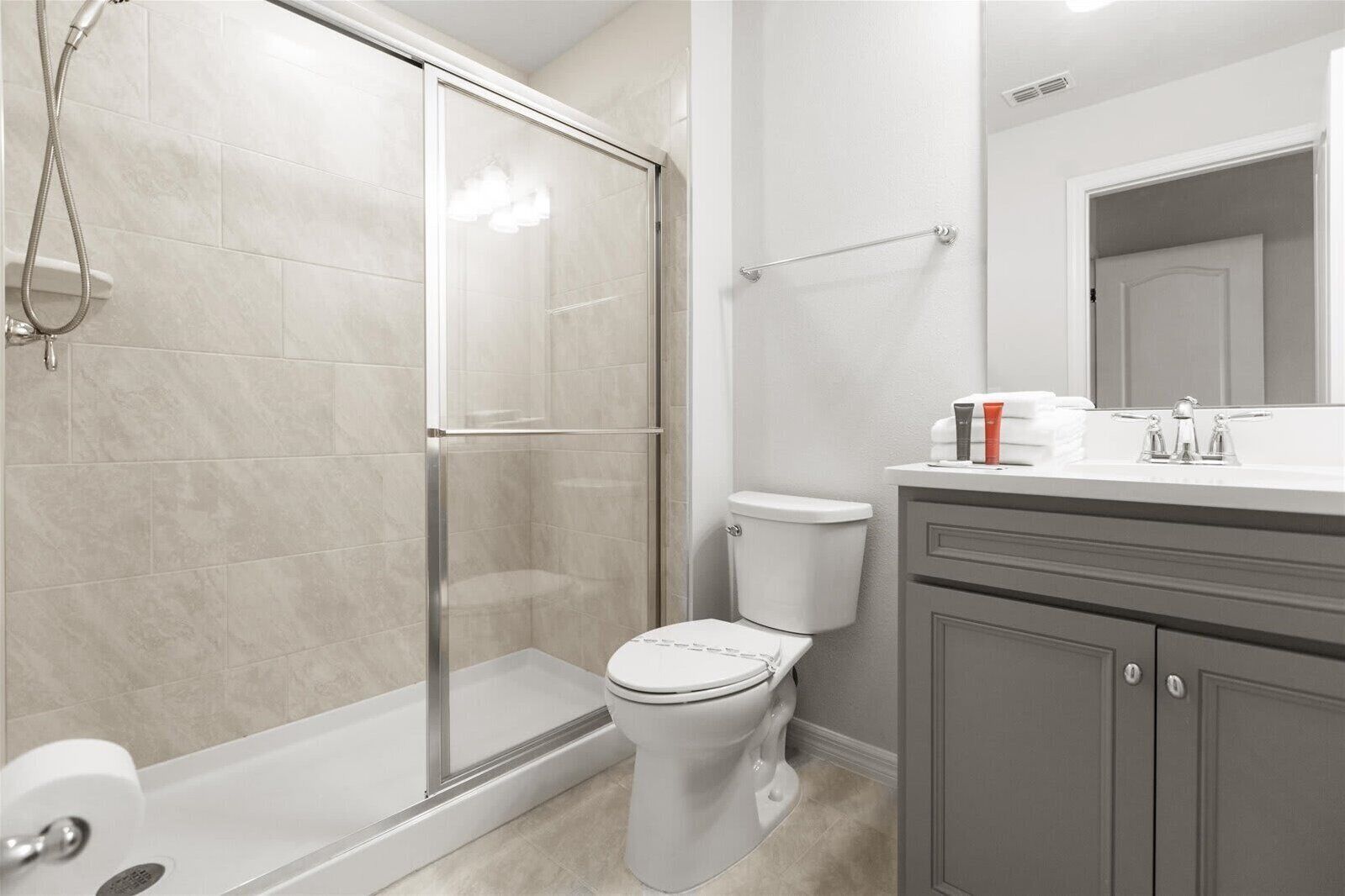 Ein modernes Badezimmer mit Duschkabine aus Glas, Toilette und Waschtisch mit Spiegel und Waschbecken.
