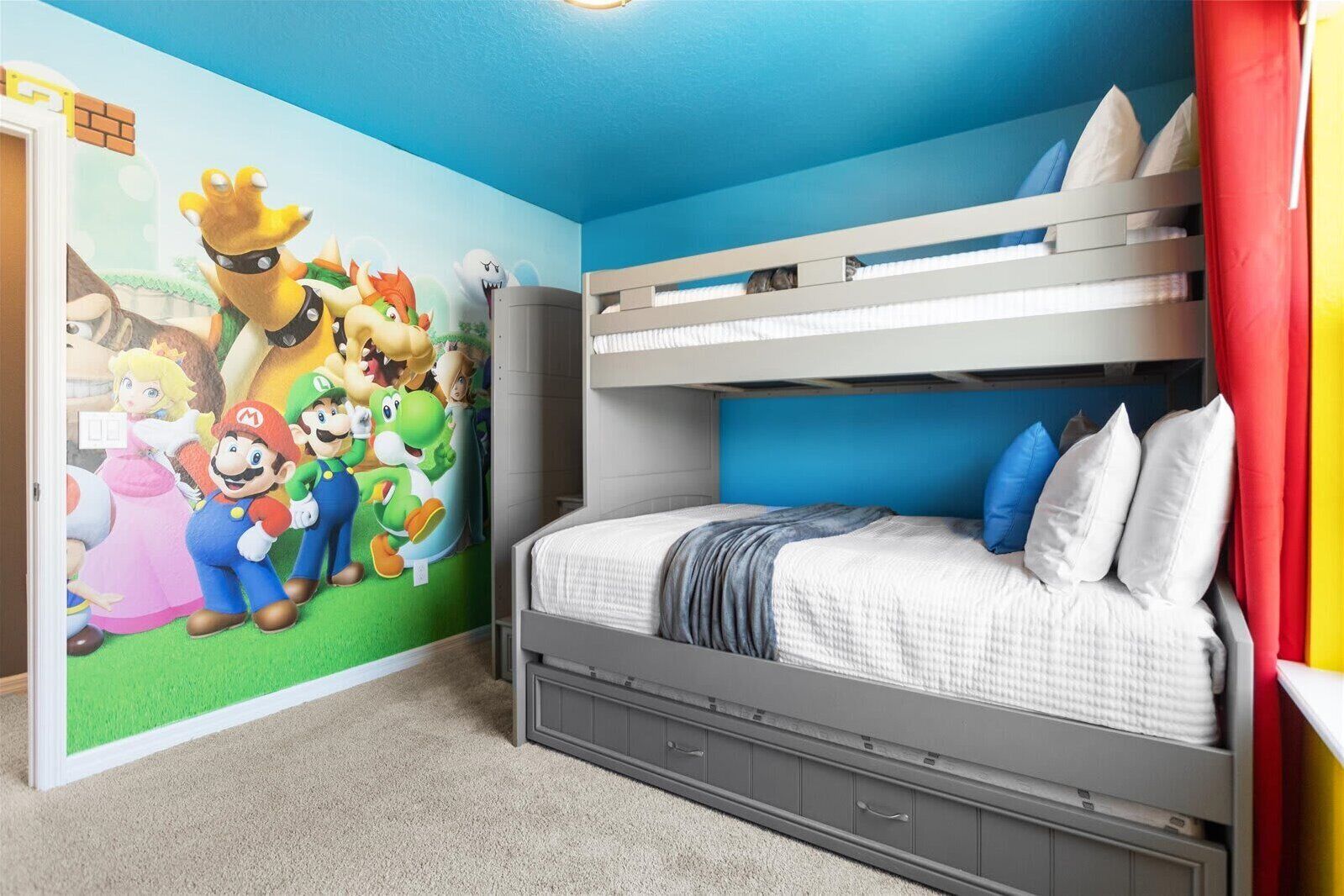 Egy hálószoba emeletes ággyal, Mario és Luigi karaktereket ábrázoló falfestménnyel és szürke komóddal.
