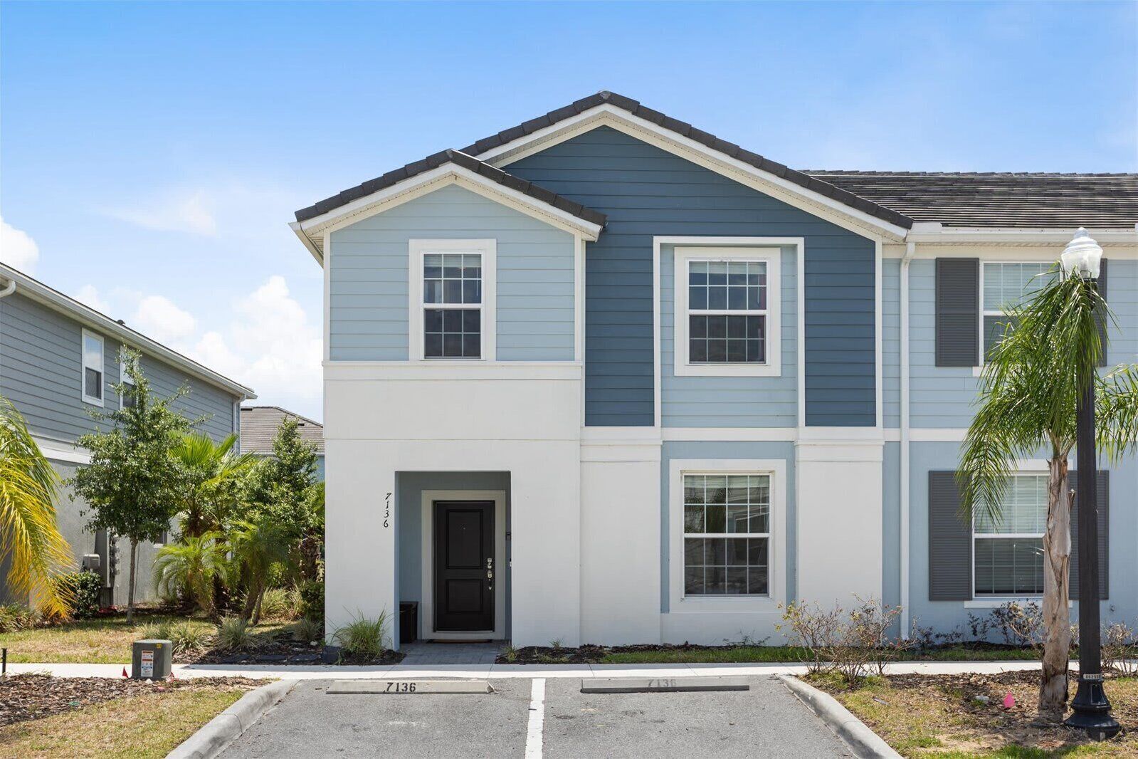 A two-story residential building with a dark blue exterior, white trim, and a front door.