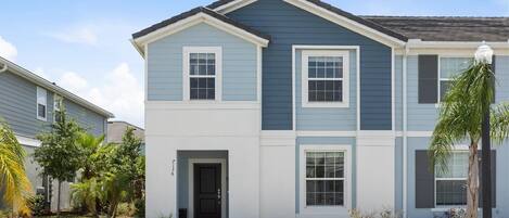 A two-story residential building with a dark blue exterior, white trim, and a front door.