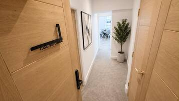 A hallway with wooden doors, a potted plant, and a framed picture on the wall.