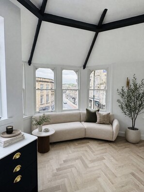 Une pièce moderne avec un canapé incurvé, une petite table ronde et une plante en pot.