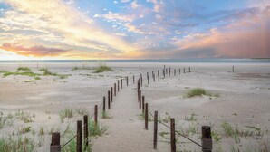 Una spiaggia sabbiosa con un recinto di legno che conduce all'acqua.