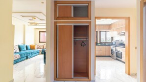 A modern apartment with a living area featuring a blue sofa and a kitchen with wooden cabinets and a washing machine. - Clean & Affordable 1BR in Agadir  24/7 Staff (Agadir)