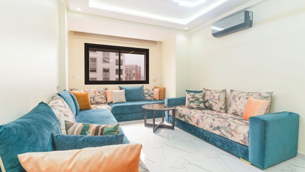 A modern living room with a sofa set, a coffee table, and a large window. - Clean & Affordable 1BR in Agadir  24/7 Staff (Agadir)