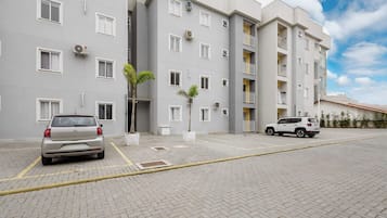 A multi-story residential building with a paved driveway and two parked cars.