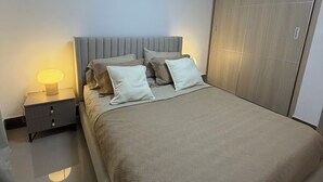 Et soveværelse med seng, sengebord, lampe og garderobeskab.