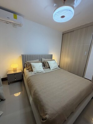 A bedroom with a bed, bedside table, lamp, and wardrobe. - Your relaxation 15 minutes away from the airport, port and beaches (Punta Cana)