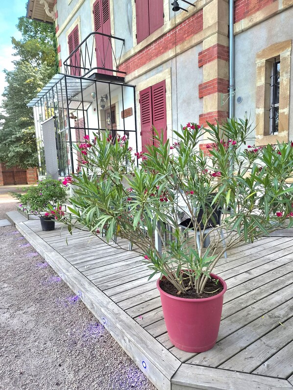 Un bâtiment avec des volets rouges, un balcon doté d’une véranda en verre et des plantes en pot sur une terrasse en bois.