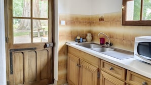 Cocina con armarios de madera, una pileta doble y un ventanal con vista a árboles.