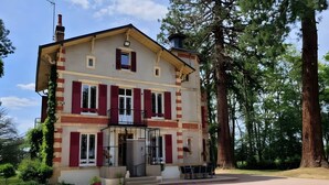Ein zweistöckiges Gebäude mit Balkon, Schornstein und einer kleinen Veranda mit Sitzgelegenheiten.