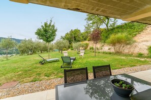 Een terras buiten met een tafel, stoelen en een gazon.