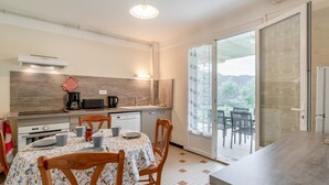 Een moderne keuken met een eethoek, een grote schuifpui naar een balkon, en uitzicht op de omgeving.
