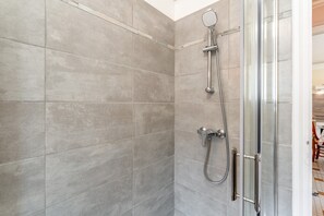A shower with a glass door, a handheld showerhead, and a wall-mounted faucet. - Gîte Des Lavandes Apartment with Mountain View and Wi-Fi (Nyons)
