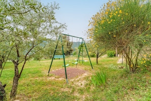A swing set in a grassy area with trees and a bench. - Gîte Des Lavandes Apartment with Mountain View and Wi-Fi (Nyons)