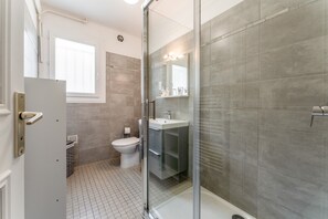 Een moderne badkamer met een douchecabine van glas, een toilet en een wastafel.