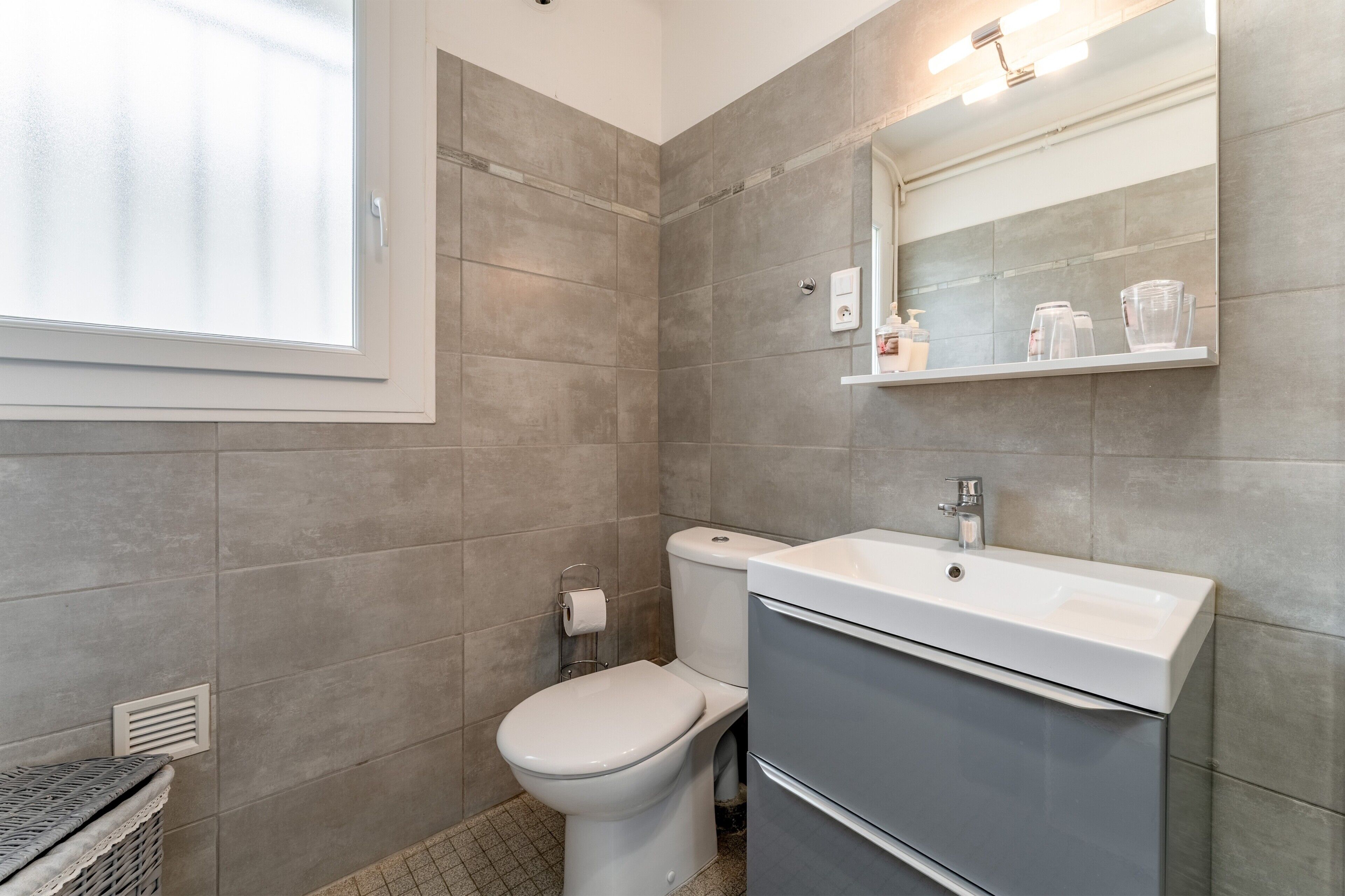 Une salle de bain comprenant des toilettes, un lavabo, un miroir et une fenêtre.