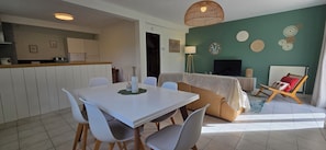 A modern living room with a sofa, a dining table with chairs, a TV, and decorative wall art. - Pretty renovated house with enclosed garden close to all amenities in Concarneau (Concarneau)