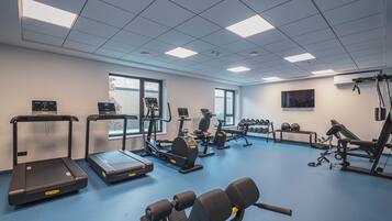 A gym with treadmills, elliptical machines, free weights, and exercise balls.