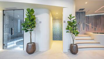 Un interior moderno con entrada de puerta de cristal, una pared curva y una escalera con barandilla metálica.
