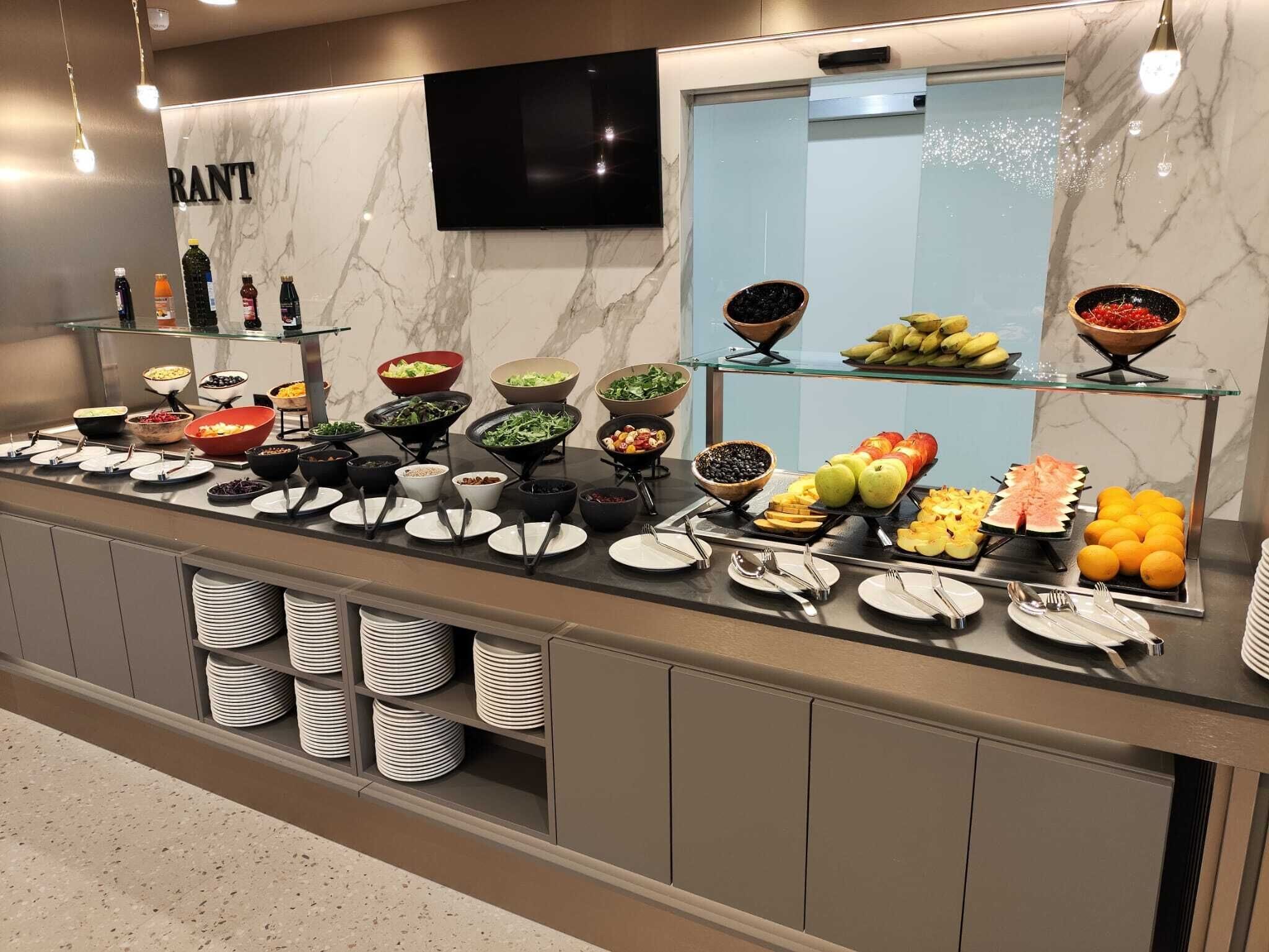 A buffet counter with various food items and a television mounted on the wall.