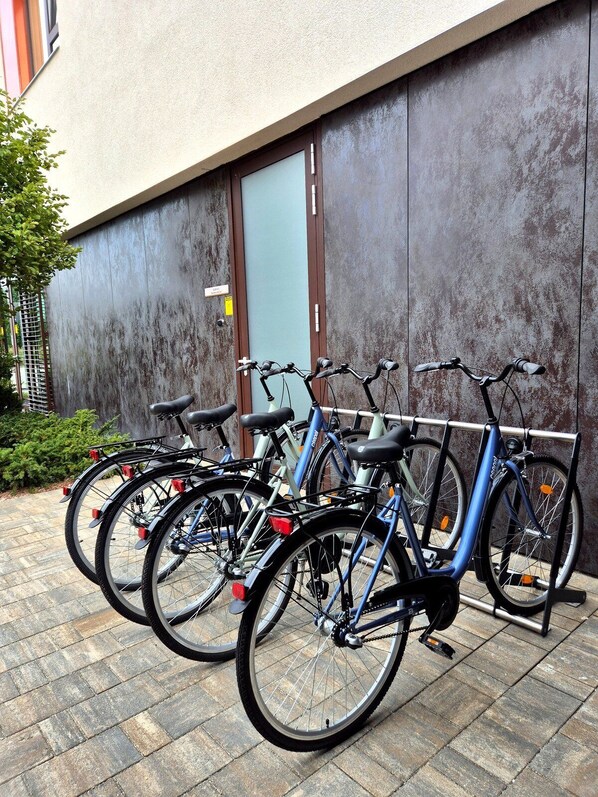 En rad cyklar står parkerade längs en byggnadsvägg.