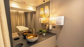 Un baño moderno con lavamanos, dos recipientes, una toalla, un espejo y un secador de manos.