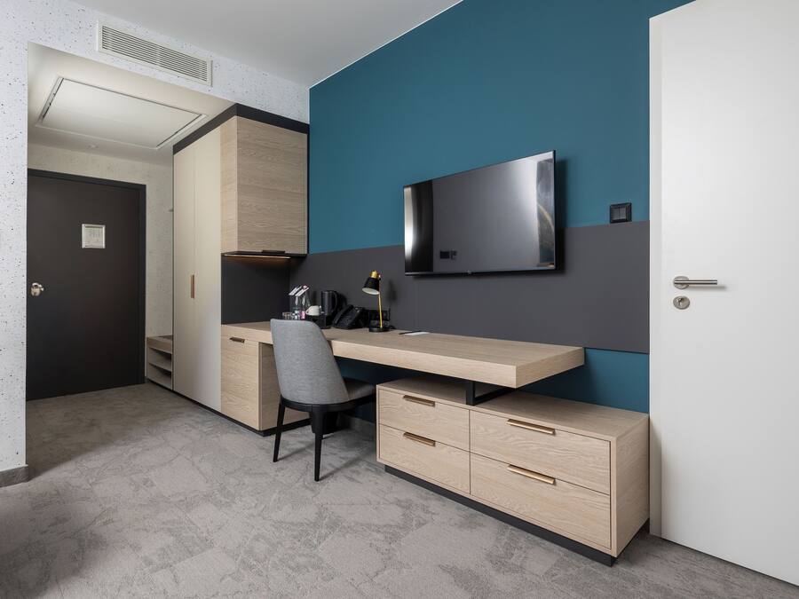 Une chambre moderne équipée d’un bureau, d’une chaise, d’une télévision et d’une armoire.