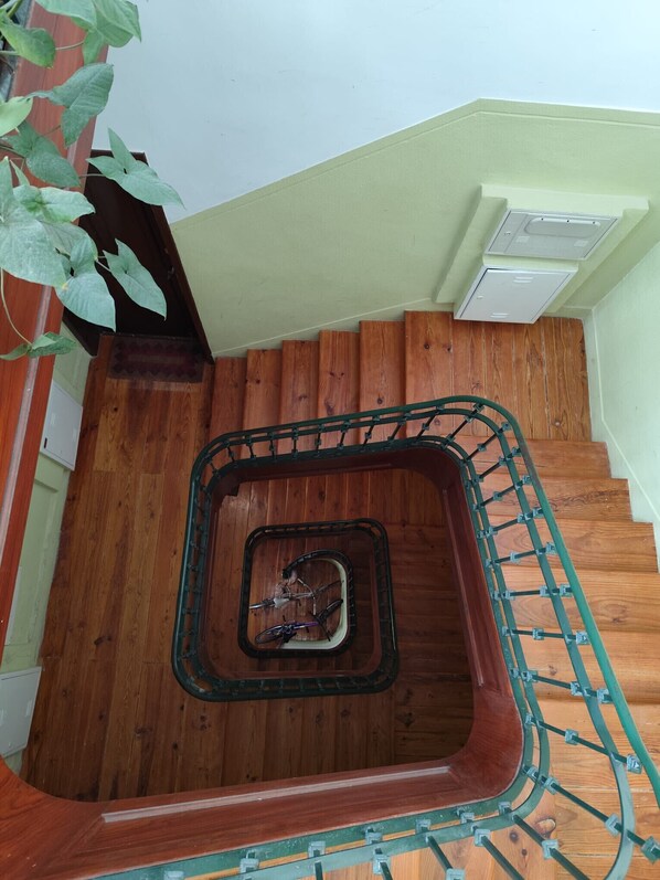 Un escalier en bois avec une rampe métallique et un escalier en colimaçon au centre.