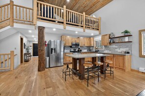 A spacious kitchen with a central island, wooden flooring, and a lofted dining area.