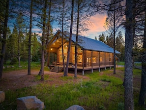 Eine Blockhütte mit Veranda, umgeben von Bäumen.