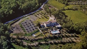 An aerial view of a property with a large house, terraced gardens, and a river. - Casa Fantone. Villa with private pool and large fenced park for absolute privacy (Poppi)
