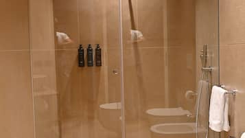 Un baño moderno con ducha envuelta en vidrio, una bañera independiente y un inodoro.