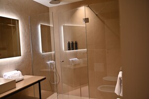 Un baño moderno con ducha envuelta en vidrio, tocador con espejo y retrete.