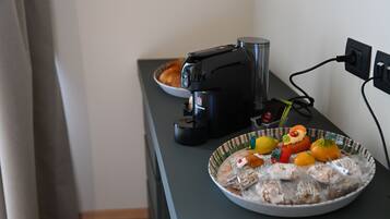 Un piano di lavoro da cucina con una macchina da caffè, una ciotola di pane e un piatto di snack assortiti.
