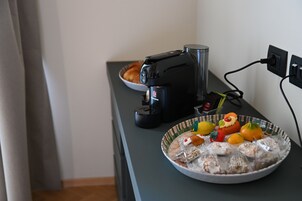 Un piano di lavoro da cucina con una macchina da caffè, una ciotola di pane e un piatto di snack assortiti.
