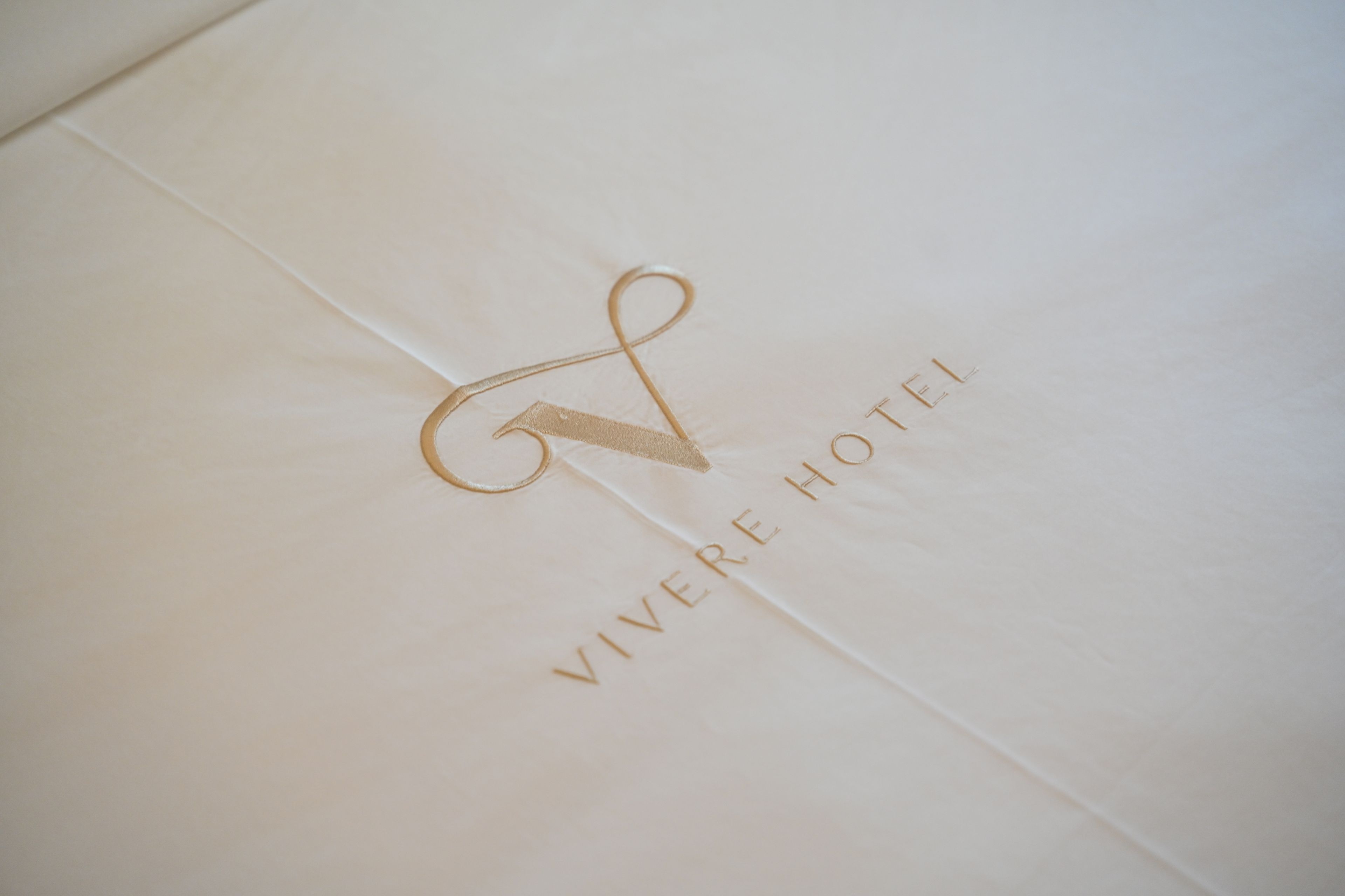 A white envelope with a gold monogram and the text 'VIVE HOTEL' embossed on it.
