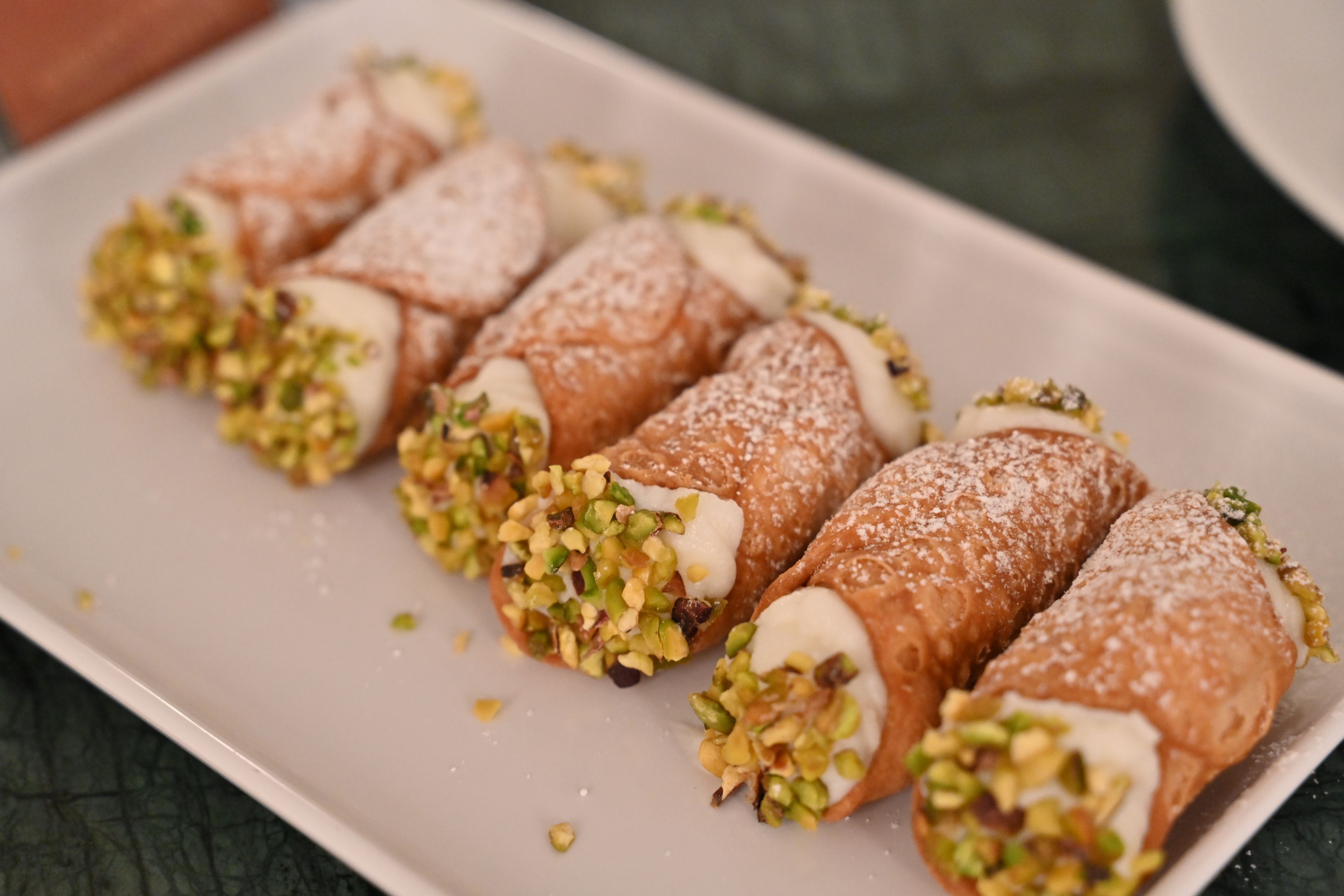 A plate of cannoli with pistachio toppings.