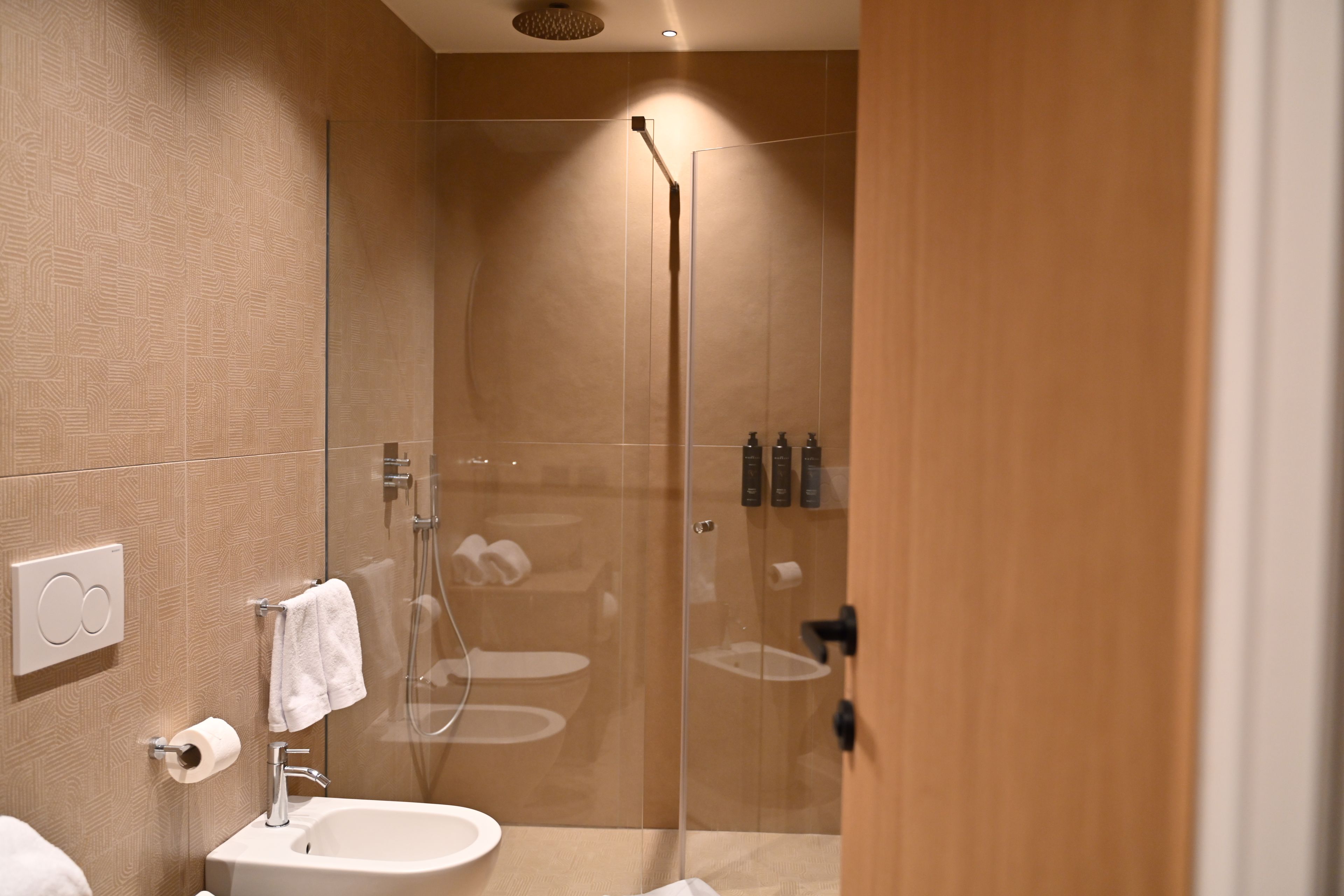 A modern bathroom with a glass-enclosed shower, a white sink, and a towel rack.