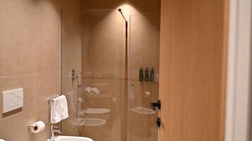 A modern bathroom with a glass-enclosed shower, a white sink, and a towel rack.