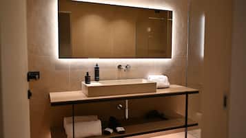 Une salle de bain moderne avec un grand miroir, un lavabo rectangulaire et un porte-serviettes.
