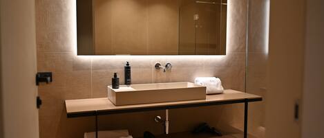 A modern bathroom with a large mirror, a rectangular sink, and a towel rack.